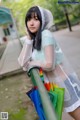 A woman in a raincoat holding a bunch of umbrellas.