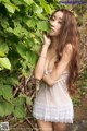 A woman in a white lingerie posing in the woods.